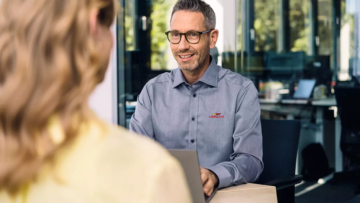 Carglass Mitarbeiter sitzt vor Laptop